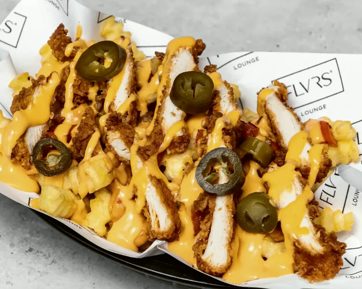Crinkled fries under cheese sauce, diced chicken, jalapeños and peppers in a paper-lined basket